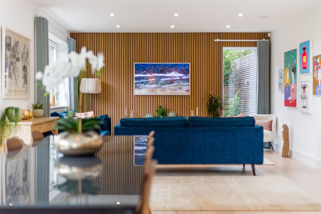 Modern open plan dining and sitting room with blue sofa and wooden wall panelling